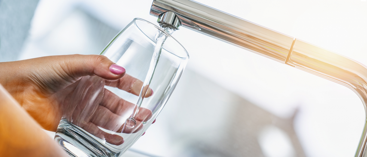 faucet pouring clean clear drinking water into a glass